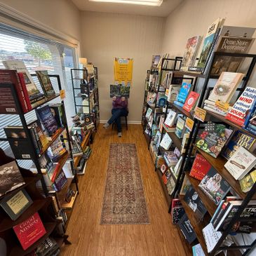 Cozy bookstore aisle filled with diverse books and a person reading at the end.
