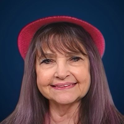 Smiling woman with purple hair and red hat.