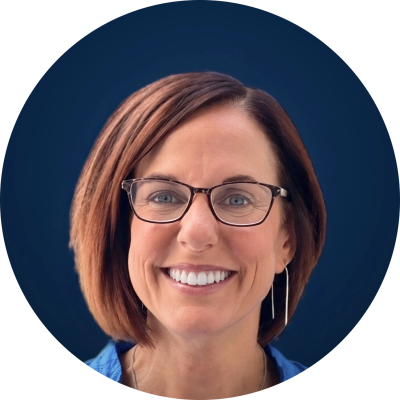 Smiling woman with glasses and short brown hair.
