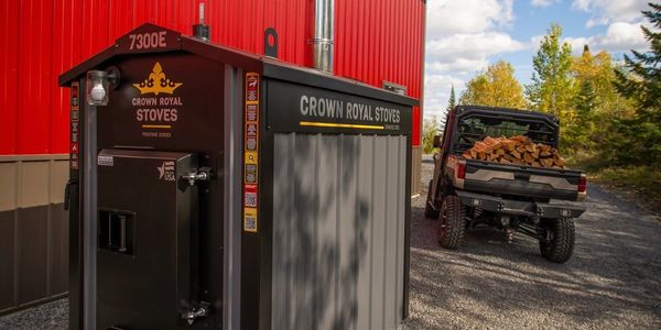 Crown Royal Stoves outdoor stove next to a red building.