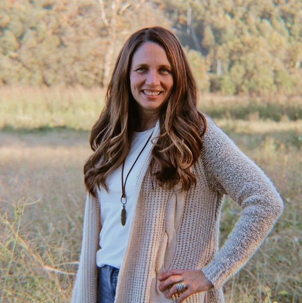 Woman smiling outdoors with long hair and cozy sweater.