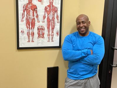 Man standing beside muscular system diagram 
