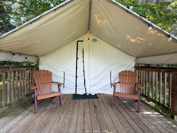 Two chairs outside a large tent on a wooden deck.