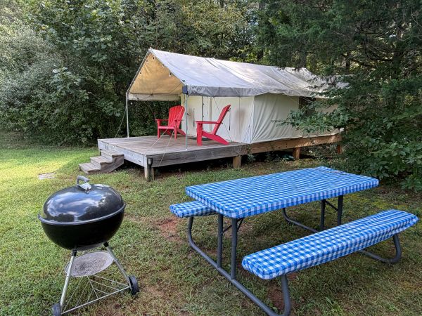Camping setup with tent, picnic table, and grill.