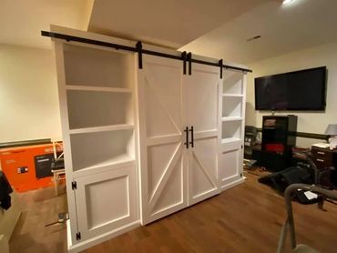 Huge barn door farmhouse style entertainment center with shelves and drawers.