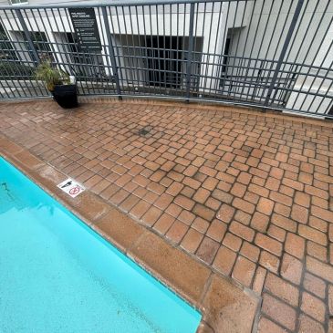 Wet poolside tiles with water splashes near a pool edge.