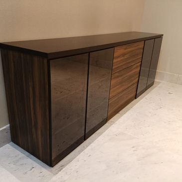 Modern wooden sideboard with glass doors in a minimalist room.