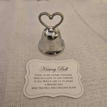 Silver heart-shaped ringing bell on fabric.