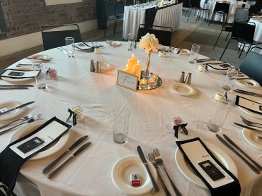 Elegant round table set for a formal event with candles and menus.