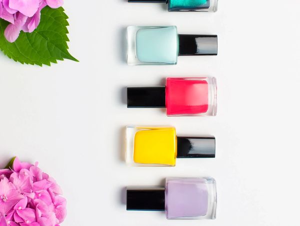 Colorful nail polish bottles with pink flowers on a white background.
