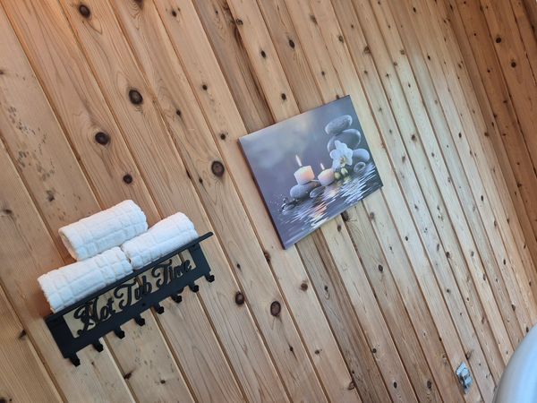 Towels on a rack and a spa-themed wall picture on wooden walls.