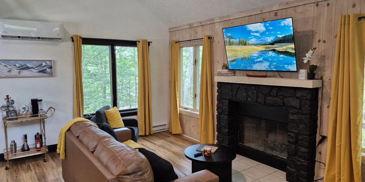 Cozy living room with a couch, armchair, and TV over a stone fireplace.