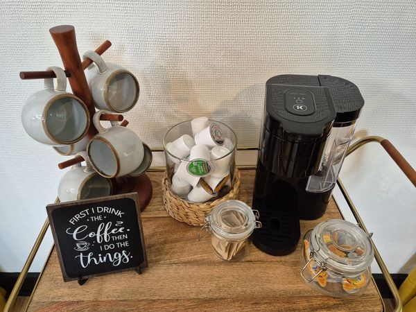 Coffee station with cups, coffee pods, and a coffee machine.