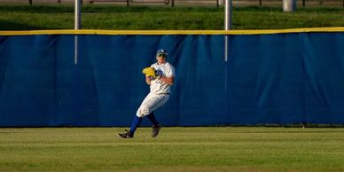 Baseball player in outfield catching a ball.