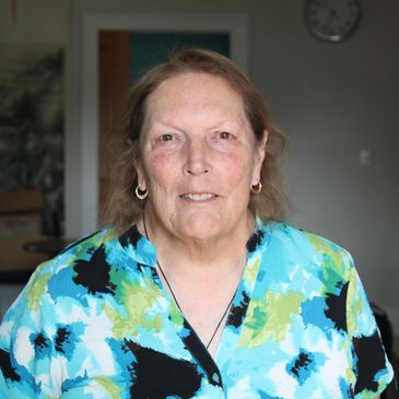 Portrait of a smiling elderly woman in a colorful blouse.