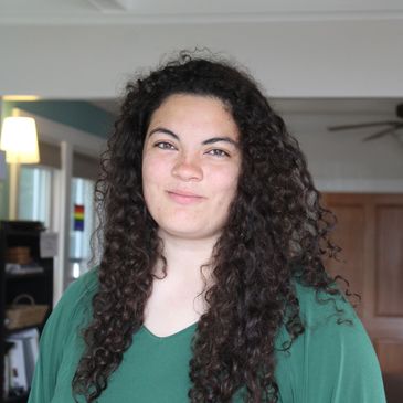 Woman with long curly hair in a green top.