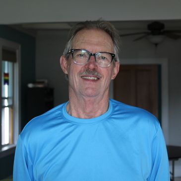 Smiling man in glasses and blue shirt indoors.