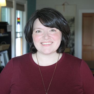 Smiling woman with short dark hair indoors.