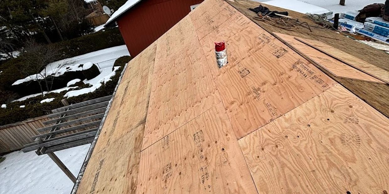 New plywood roof decking installed on a snowy day.