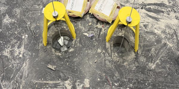 Two yellow weights over floor holes with cables.