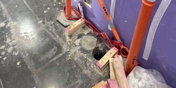 Construction site with exposed floor and pipes.