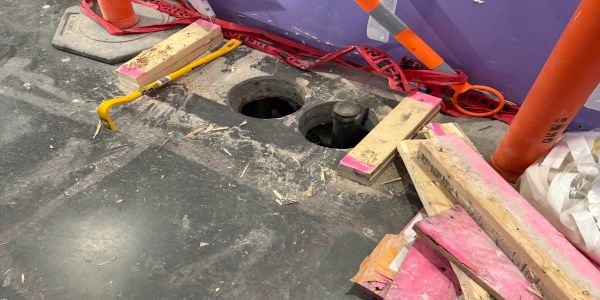 Construction site floor with holes and tools.