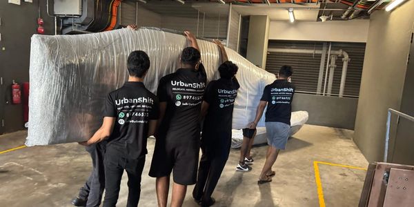 A team carrying a large wrapped item in a parking garage.