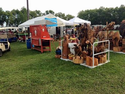 Wooden animal sculptures displayed at an outdoor market.