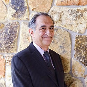 Man in a suit smiling near a stone wall.