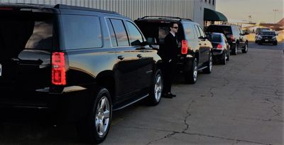 Chauffeur Standing with a motorcade of Black SUVs