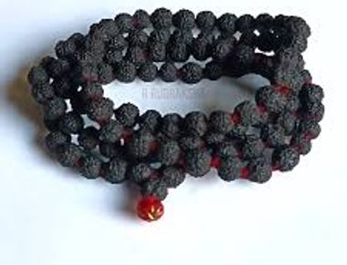 A coiled black bead necklace with a single red bead.