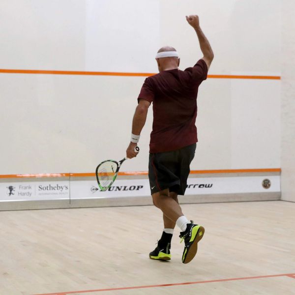 Man playing squash celebrating with a raised fist.