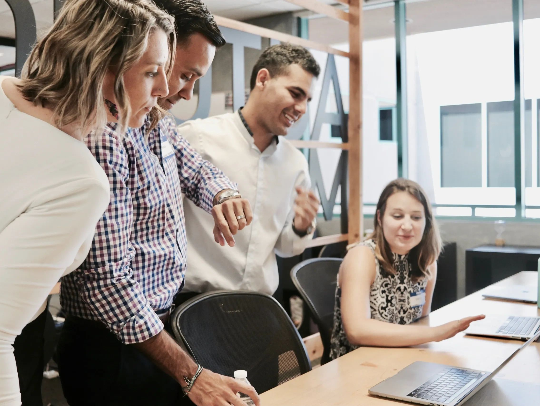 A group of colleagues collaborating around a laptop in a modern office.