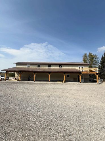 Large two-story building with a metal roof and wooden supports.