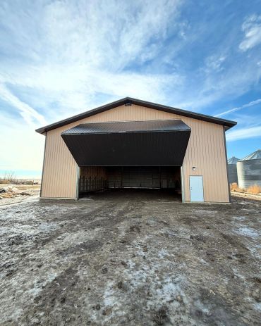 Large open shed with a wide entrance and a metal roof.