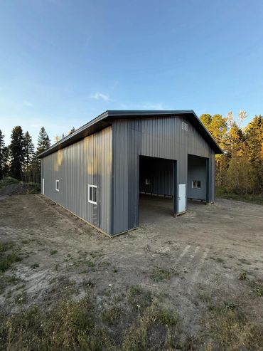 A large gray metal building in a rural area.