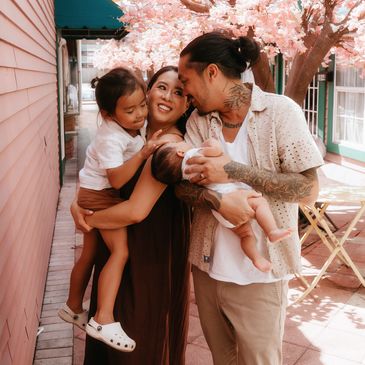 Family enjoying moment under pink blossoms.