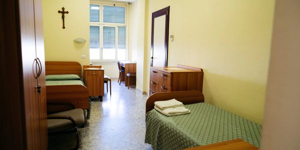 A simple, clean room with two single beds and minimal wooden furniture.