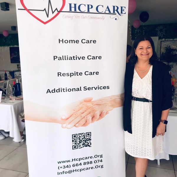 Woman standing next to HCP Care service banner offering home and palliative care.