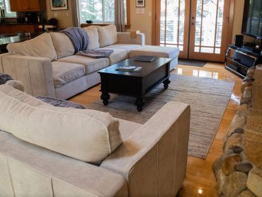Sala acogedora con sofás beige y mesa de centro negra.