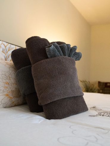Toallas enrolladas apiladas sobre una cama blanca.