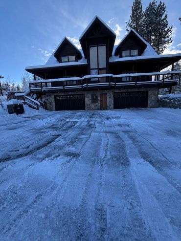Casa grande de madera en la nieve bajo cielo azul.