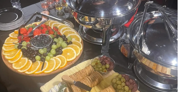Elegant fruit and cheese platter with crackers, olives, and strawberries on a buffet table.