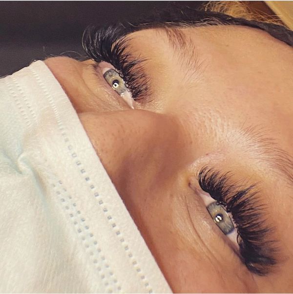 Close-up of eyes with long, voluminous eyelash extensions and a face mask.