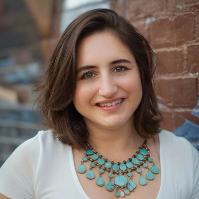 Smiling woman wearing a white shirt and turquoise statement necklace.