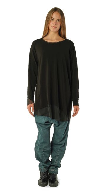 Femme portant un pull noir long et un pantalon bleu décontracté.