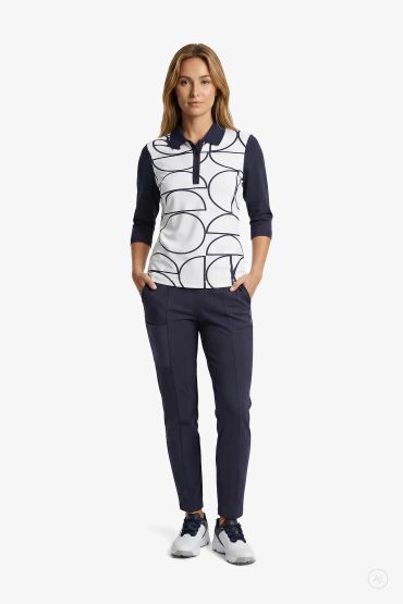 Woman wearing a modern casual outfit with navy pants and white patterned top.