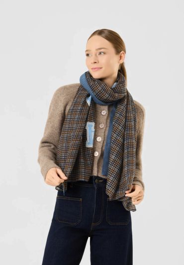 Woman wearing a checkered scarf and brown cardigan.