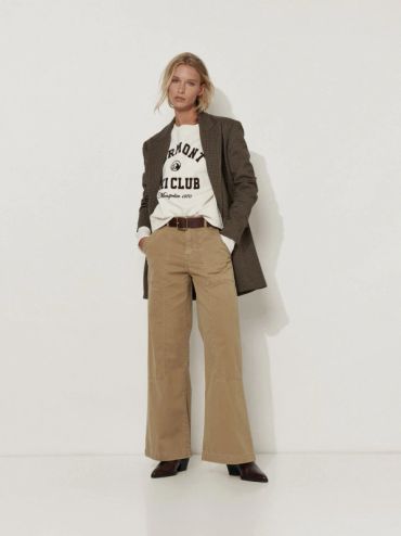 Femme posant en tenue décontractée avec blazer, t-shirt et pantalon large.