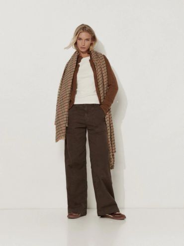 Femme posant en tenue décontractée marron et crème.